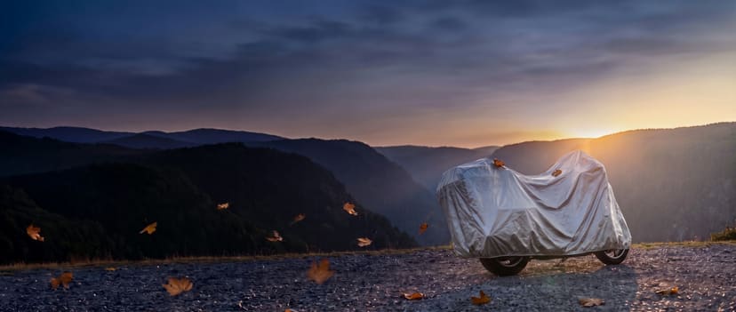 Silver cover on a touring motorcycle at a canyon overlook at sunset with leaves blowing past