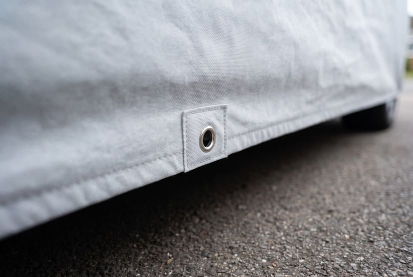 Close up of a reinforced patch with a metal grommet in the side hem of a light grey Weatherproof Max cover