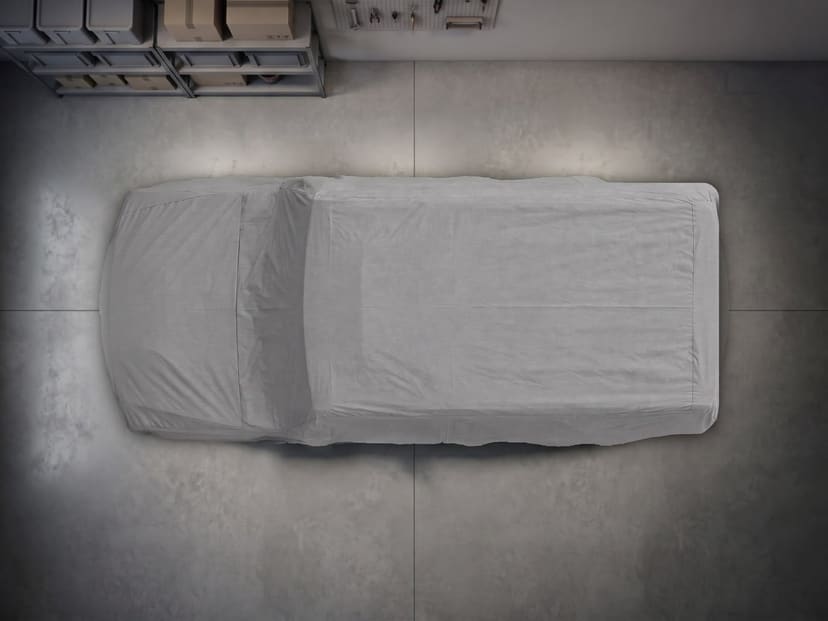 Top-down view of a grey indoor cover fitted over a Hummer on a concrete garage floor.
