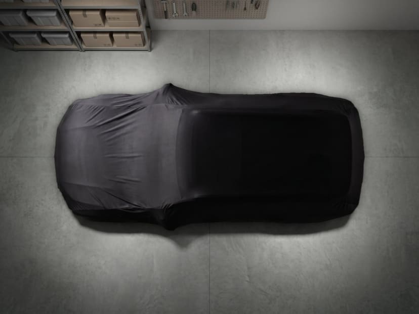 Top-down view of a black stretch cover fitted over an SUV on a concrete garage floor.